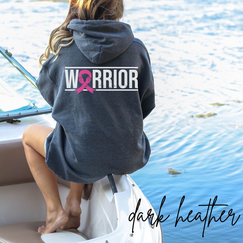 May include: Dark heather grey hoodie with a pink ribbon and the word "WARRIOR" printed on the back.