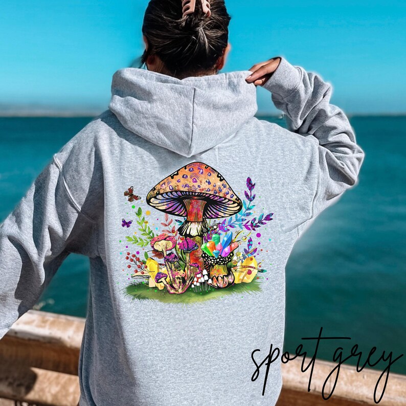 May include: A gray hooded sweatshirt with a colorful mushroom graphic on the back. The mushroom is surrounded by flowers and butterflies. The text "sport grey" is printed on the bottom of the image.