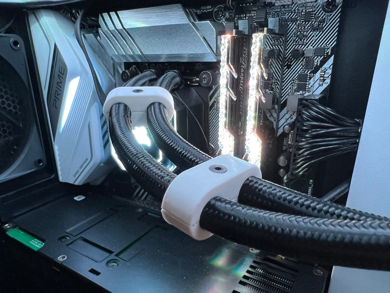 K&ouml;nnte beinhalten: Nahaufnahme der internen Komponenten eines Computers, darunter ein wei&szlig;es Motherboard mit dem aufgedruckten Wort "PRIME", schwarze Kabel und wei&szlig;e Kabelmanagementklemmen.