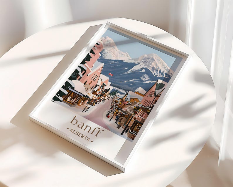 A framed poster of a snowy mountain town in Alberta, Canada, with colorful buildings and a ski lift.