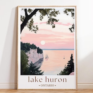 Può includere: Una stampa artistica incorniciata con un sereno paesaggio del Lago Huron al tramonto. L'opera raffigura un cielo rosa e arancione, scogliere bianche, barche a vela e alberi verdi. Il testo "lake huron • ontario" è stampato in basso.