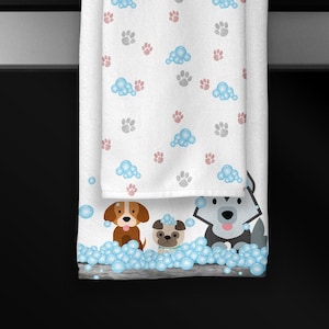 May include: A white kitchen towel with a pattern of paw prints and blue bubbles. The towel has a border of blue bubbles and three cartoon dogs in a bathtub with bubbles.