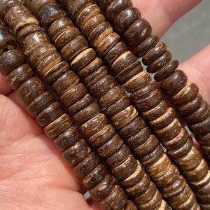 Puede incluir: Primer plano de una pila de cuentas de madera marrón. Las cuentas son redondas y tienen un aspecto natural y rústico.