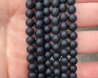 May include: A strand of black matte round beads. The beads are smooth and have a slightly textured surface.