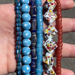 May include: A collection of beaded bracelets in various designs and colors. The bracelets feature blue, white, and red beads, including polka dots, stripes, and patterned shapes. The beads are strung together, creating a colorful accessory.