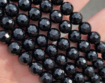 May include: A strand of black faceted gemstone beads. The beads are round and have a shiny, polished finish.