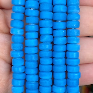 May include: A strand of turquoise blue glass beads. The beads are round and have a smooth, polished finish.