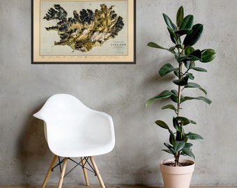 May include: A vintage map of Iceland with a black frame. The map is in a relief style, showing the topography of the island. The map is printed on a cream-colored paper with brown and green accents.