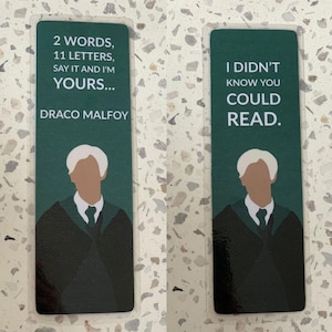 Könnte beinhalten: Zwei grüne Lesezeichen mit einem Charakter aus der Harry-Potter-Serie. Das erste Lesezeichen hat den Text "2 WORDS, 11 LETTERS, SAY IT AND I'M YOURS... DRACO MALFOY". Das zweite Lesezeichen hat den Text "I DIDN'T KNOW YOU COULD READ."