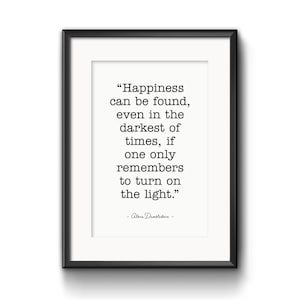 May include: A framed print with a white background and black text. The quote reads: "Happiness can be found, even in the darkest of times, if one only remembers to turn on the light." The author is Albus Dumbledore. The frame is black.