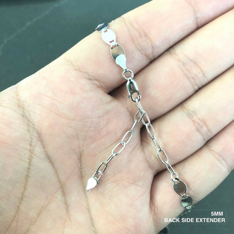 May include: Silver chain necklace with a 5mm extender. The chain is made of small oval links and has a lobster clasp closure. The extender is a small chain with a lobster clasp on one end and a jump ring on the other.