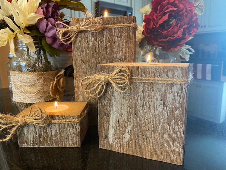 Puede incluir: Tres portavelas de madera r&uacute;stica con un acabado blanco desgastado. Cada portavelas tiene un lazo de cuerda natural y est&aacute; dise&ntilde;ado para sostener una vela de t&eacute;.