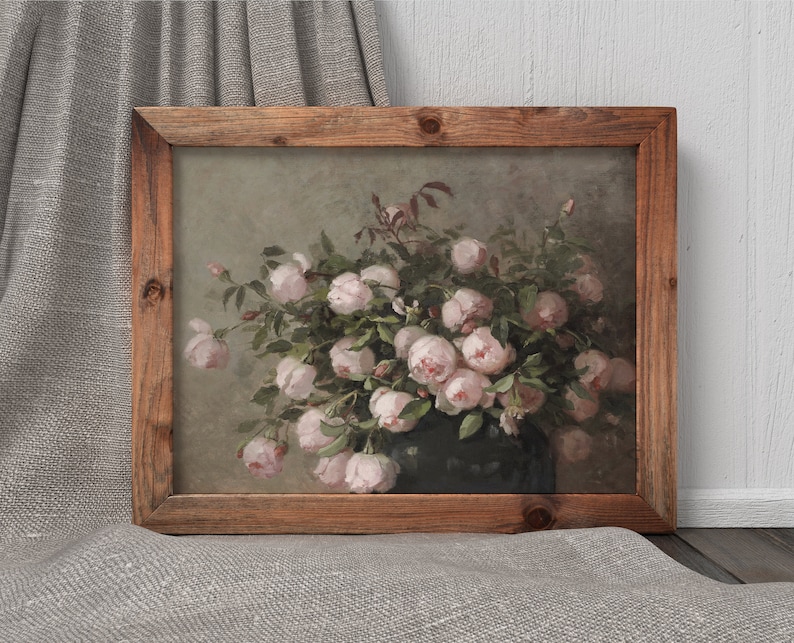 May include: A framed floral print featuring a bouquet of pink roses in a dark vase. The artwork has a vintage aesthetic, with a wooden frame and a soft, muted color palette. The roses are in full bloom, with green leaves.