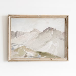 May include: A framed watercolor painting of a mountain range with a light brown wooden frame. The painting depicts a mountain range with a light brown wooden frame. The mountains are painted in shades of gray, brown, and white, with a hint of green in the foreground.