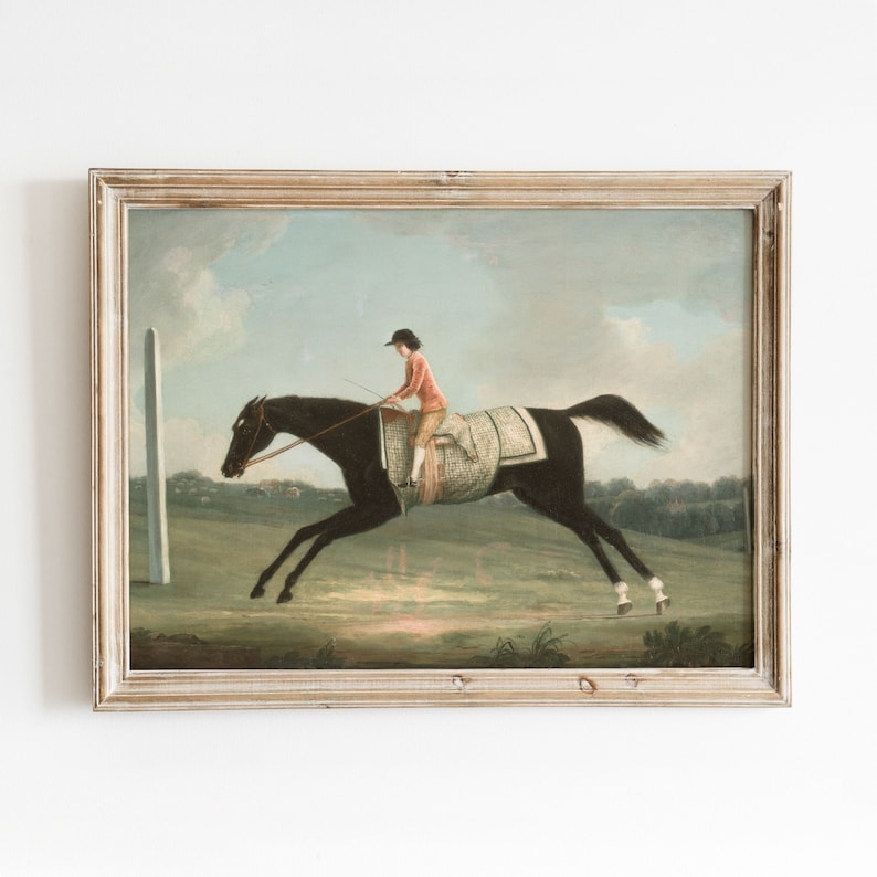 May include: An antique framed print depicts a horse race scene. A jockey in a red coat and black hat rides a dark horse at full gallop. The horse wears a checkered blanket. The background shows a green field, a white post, and a cloudy sky.