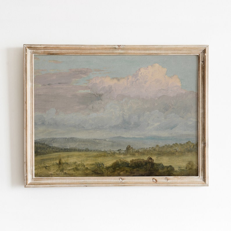 May include: A framed landscape painting depicting a field with trees and a cloudy sky. The sky is a soft blue with pink and purple clouds. The field is green with brown trees in the distance.
