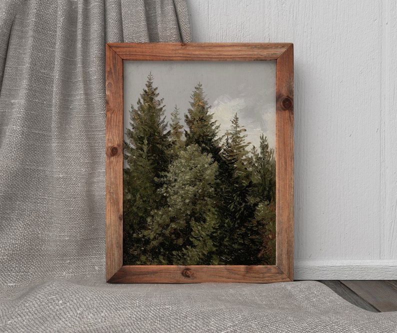 Op de afbeelding: Een ingelijste print van een bos sc&egrave;ne met hoge, groene dennenbomen tegen een lichtblauwe lucht. De bomen staan dicht bij elkaar, waardoor een gevoel van diepte en perspectief ontstaat.