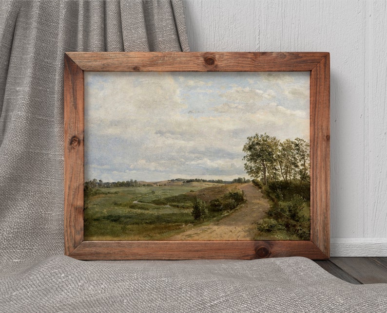 Pu&ograve; includere: Un dipinto incorniciato di un paesaggio rurale con una strada sterrata che attraversa un campo. Il cielo &egrave; nuvoloso e gli alberi sono verdi.