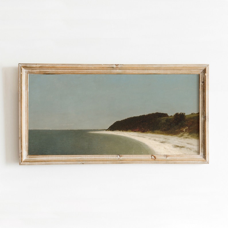 May include: A framed painting of a seascape with a sandy beach and a green grassy hill in the background. The sky is a light blue and the water is a light green.