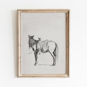 May include: A black and white pencil drawing of a horse with a saddle on its back, framed in a light wood frame.