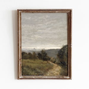 Op de afbeelding: Een ingelijst schilderij van een landschap met een kronkelend zandpad dat door een veld met groen gras en bomen loopt. De lucht is een gedempte grijs met een paar wolken.