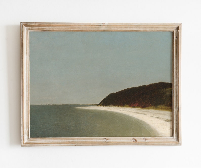 May include: A framed painting of a seascape with a sandy beach, a curved shoreline, and a forested hillside in the distance. The sky is a light blue, and the water is a muted green.