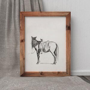 May include: A black and white pencil drawing of a horse with a saddle, framed in a rustic wooden frame.