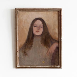 以下が含まれることがあります： 長い茶色の髪をした女性が、薄いグレーのセーターを着て目を閉じている油絵の額縁。絵は薄い茶色の背景です。