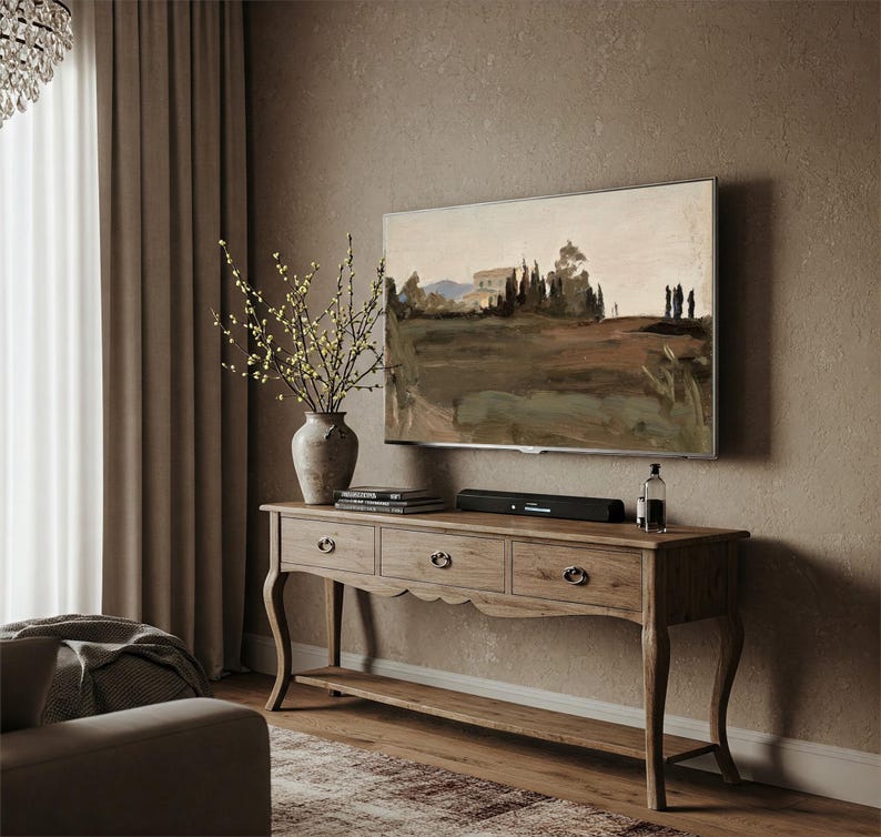 May include: A wooden console table with three drawers and a lower shelf. The table is painted in a light brown color and has a distressed finish. A flat screen TV is mounted on the wall above the table. A vase with yellow flowers sits on the table.