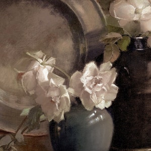 K&ouml;nnte beinhalten: Ein Stillleben mit wei&szlig;en Rosen in einer blauen Vase, im Hintergrund ein silbernes Tablett und eine dunkelbraune Keramikvase.