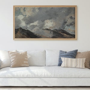 May include: A white sofa with a framed painting of a mountain landscape with a cloudy sky above. The sofa has three cushions, one blue, one beige, and one with a striped pattern.