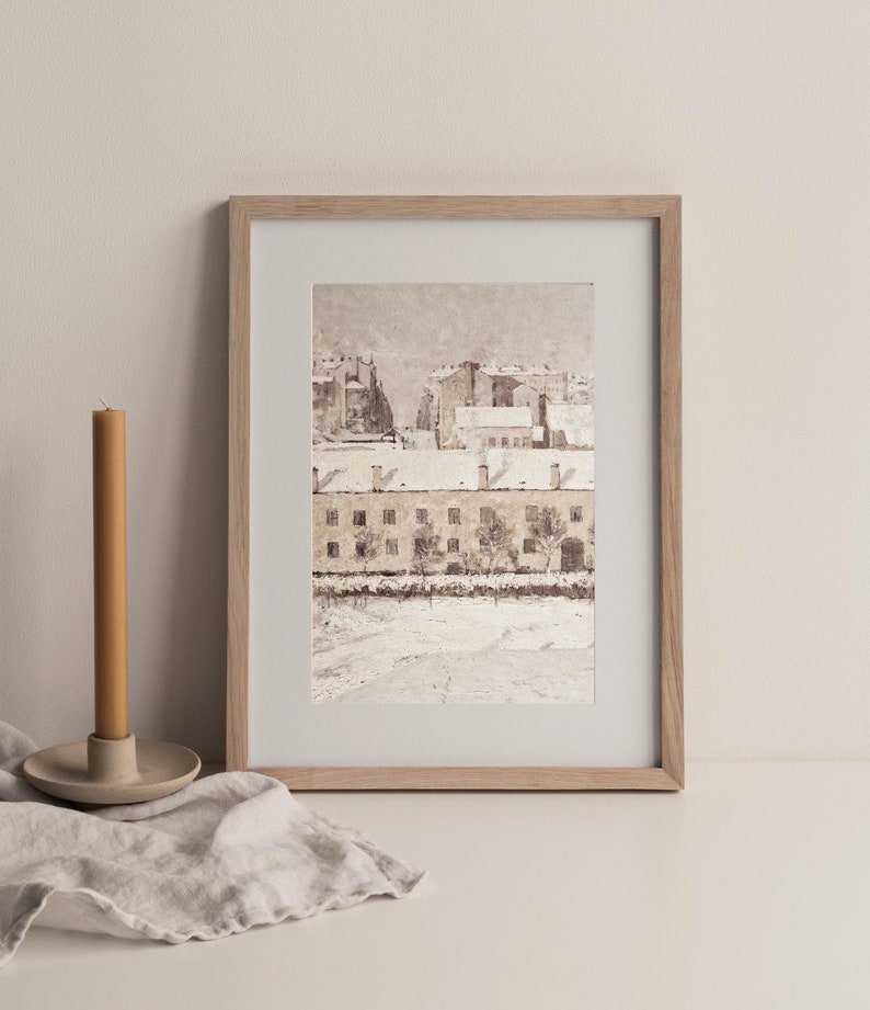 May include: A framed watercolor painting of a snowy cityscape with buildings and trees. The buildings are painted in shades of brown and white, and the trees are painted in shades of green and brown. The painting is set against a white background.