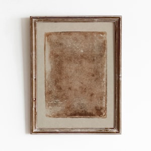 Puede incluir: Un marco de madera marrón con un fondo beige texturizado. El marco está vacío y listo para una imagen o una obra de arte.