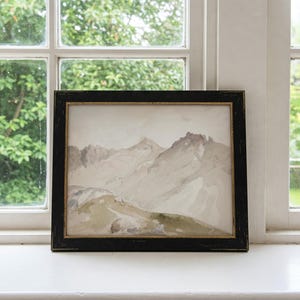 May include: A framed watercolor painting depicting a mountain range with a light brown and gray color scheme. The mountains are depicted in a realistic style with a focus on the peaks and valleys.