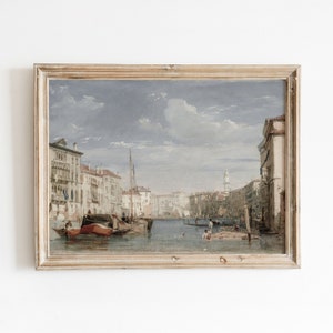 K&ouml;nnte beinhalten: Ein Vintage-Gem&auml;lde in einem Holzrahmen zeigt eine Kanalszene in Venedig, Italien. Das Gem&auml;lde zeigt einen Wasserweg, der von Geb&auml;uden, Booten und Menschen ges&auml;umt ist. Der Himmel ist hellblau mit wei&szlig;en Wolken.
