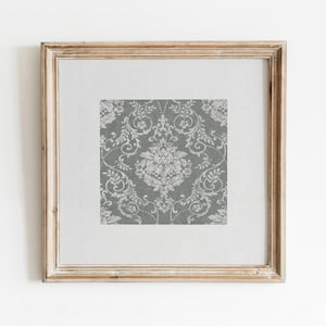 May include: A framed print of a gray and white damask pattern. The frame is a light wood color.