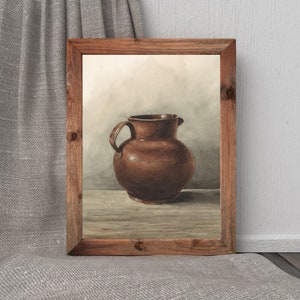 May include: A watercolor painting of a brown ceramic pitcher in a wooden frame. The pitcher has a rounded body and a wide mouth.