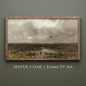 May include: A framed landscape painting depicting a marsh with a cloudy sky and a flock of birds flying overhead. The frame is made of wood with a maple and oak finish. The text "MAPLE + OAK | Frame TV Art" is printed below the painting.