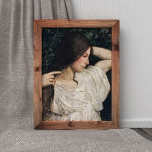 May include: A framed painting of a woman with long brown hair, wearing a white dress, with her head resting on her arm. The painting is set against a dark green background.
