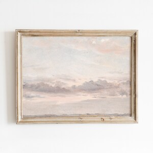 Pode incluir: Uma pintura emoldurada de um céu nublado com uma suave combinação de cores rosa e cinza. A pintura está em uma moldura de madeira clara.