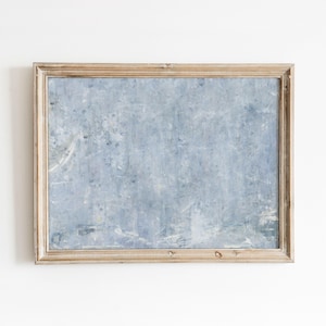 May include: A light blue canvas painting in a simple, wooden frame. The frame is a light brown color with a slightly distressed finish.