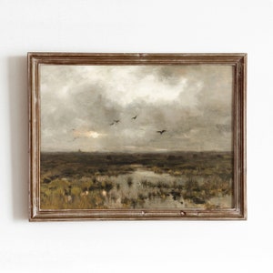 Pode incluir: Uma pintura emoldurada que retrata uma paisagem com um céu nublado e um pântano com água e juncos. A pintura está em tons suaves de marrom, cinza e verde.