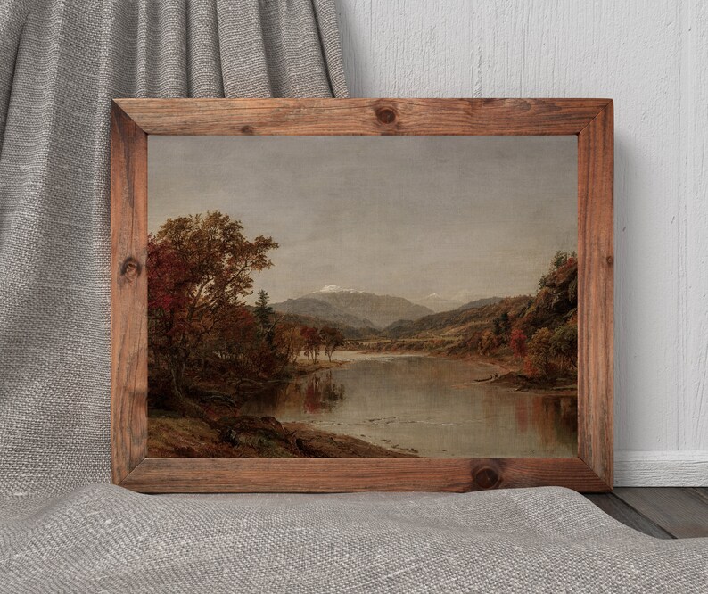 K&ouml;nnte beinhalten: Gerahmtes Landschaftsgem&auml;lde mit einer ruhigen Seeszene und Bergen im Hintergrund. Das Kunstwerk zeigt Herbstlaub in Rot- und Braunt&ouml;nen unter einem bew&ouml;lkten Himmel. Der Holzrahmen verleiht einen rustikalen Touch.