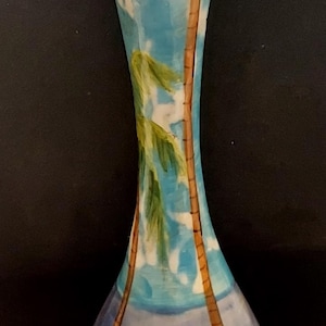 May include: A blue and white ceramic vase with a palm tree design. The vase has a wide mouth and a narrow base.