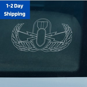 May include: A white outline of a military bomb disposal badge on a dark blue background. The badge features a bomb with wings and a laurel wreath.