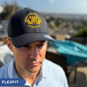 May include: Black baseball cap with a gold embroidered logo that reads "Undersea Special Mission Systems NAVSEA PMS-391".