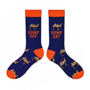 May include: Navy blue socks with orange heels and cuffs, featuring a camel pattern and the words "HUMP DAY" in orange. These socks are designed for comfort and style, perfect for everyday wear.