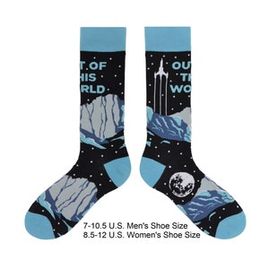 May include: Black socks with a space-themed design. The socks have blue cuffs and toes, with a design of mountains, a rocket, and the moon. Text on the socks reads "OUT OF THIS WORLD".