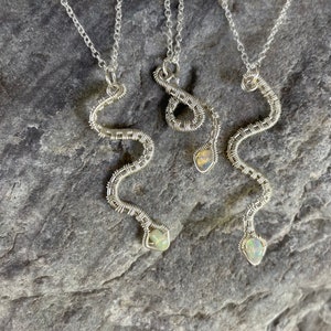 以下が含まれることがあります： オパールストーンが付いたシルバーのスネークネックレス3本。各ネックレスは、ワイヤーで巻かれた蛇の細かなデザインが特徴です。