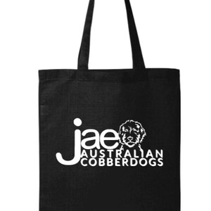Puede incluir: Bolso tote negro con texto blanco e ilustraci&oacute;n de perro. El texto dice "jae AUSTRALIAN COBBERDOGS". El bolso tiene dos asas largas para llevar al hombro.